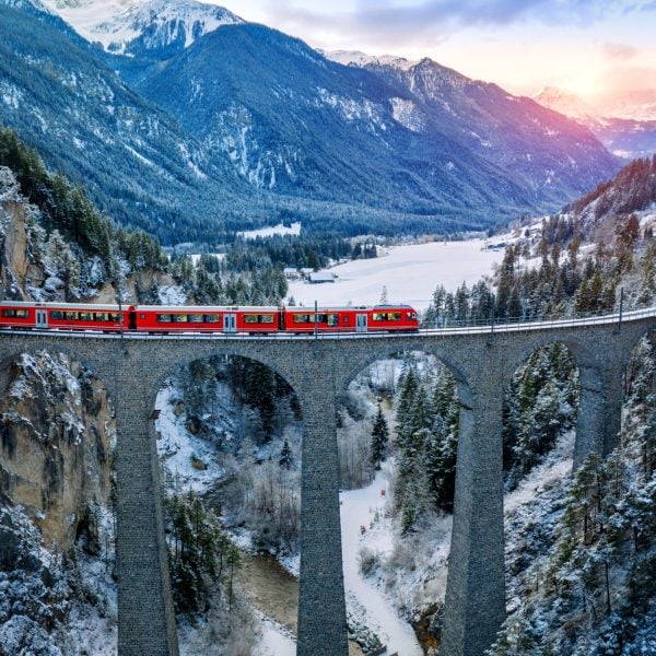 Aerial view of Train passing through famous mountain in Filisur, Switzerland. Landwasser Viaduct world heritage with train express in Swiss Alps snow winter scenery.